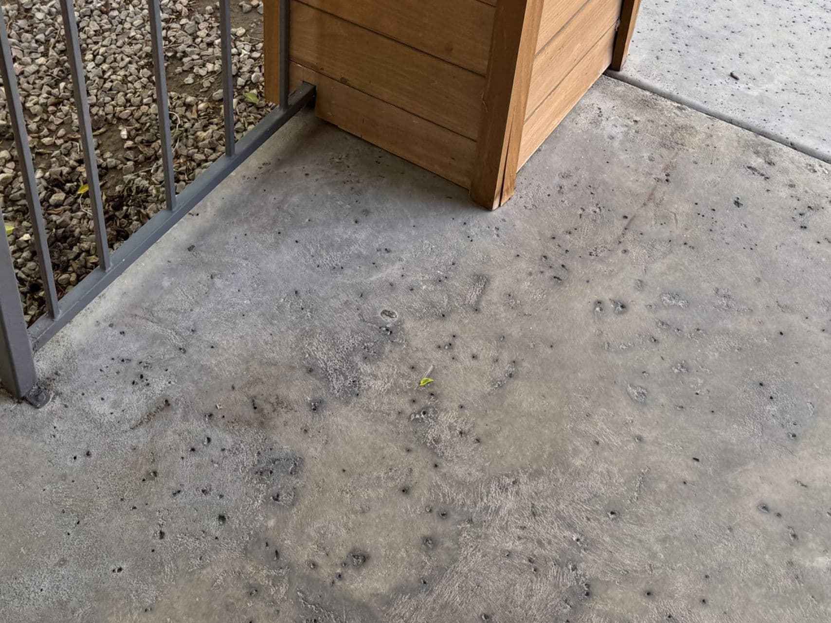 Concrete surface with scattered markings and wooden structure near a gate.