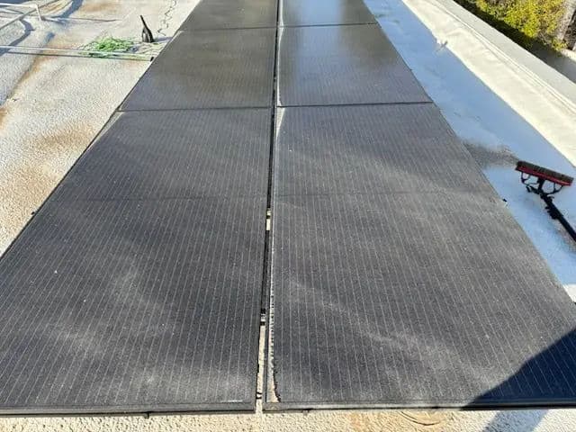 Solar panel installation on a rooftop with clean, dark panels and a clear sky background.